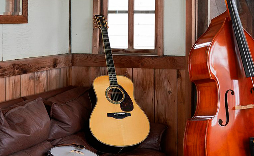 Kytara YAMAHA LS6 ARE NATURAL položená na gauči